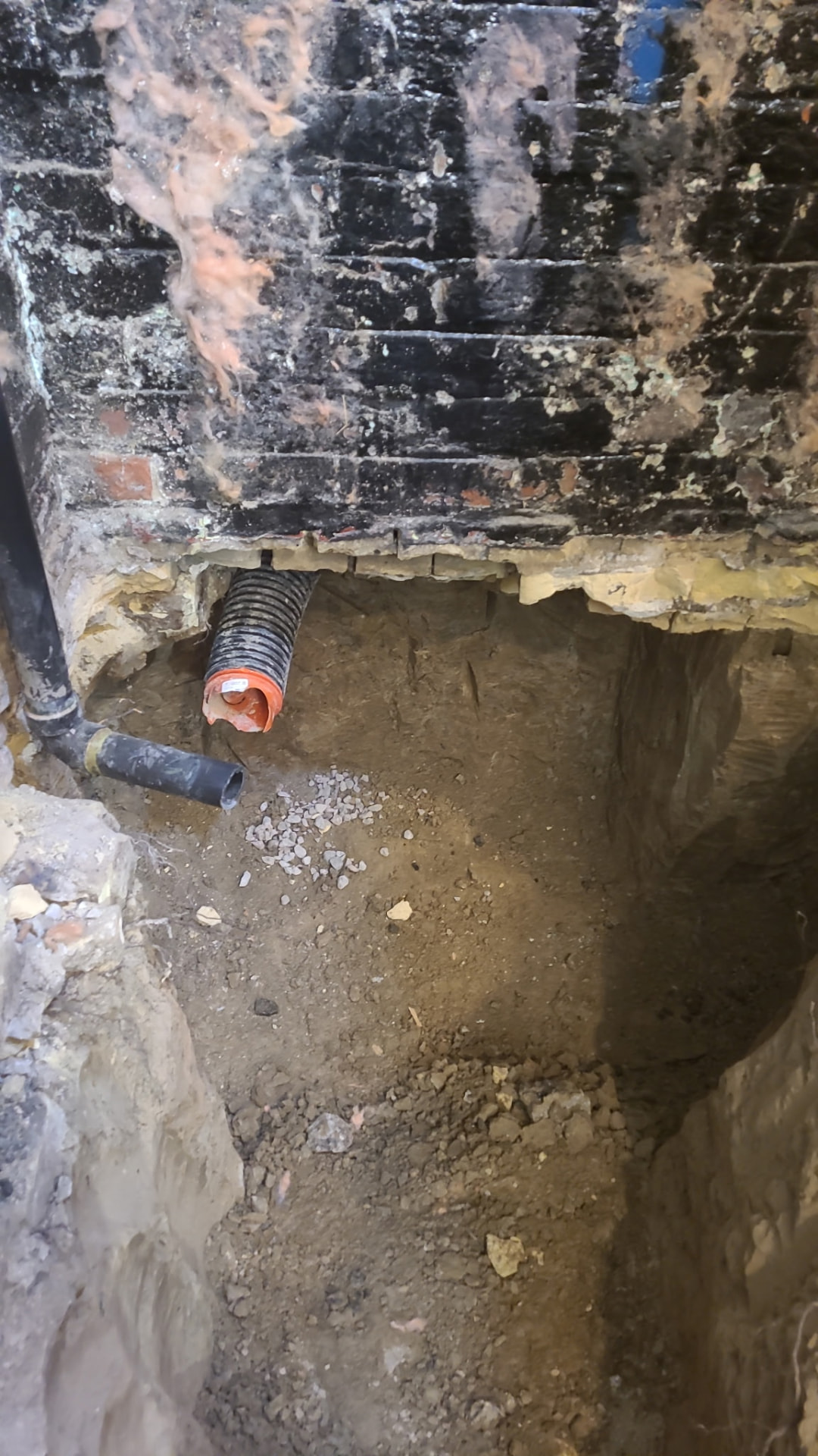 Excavated underpinning pit with weeping tile and drainage pipe below the original footing