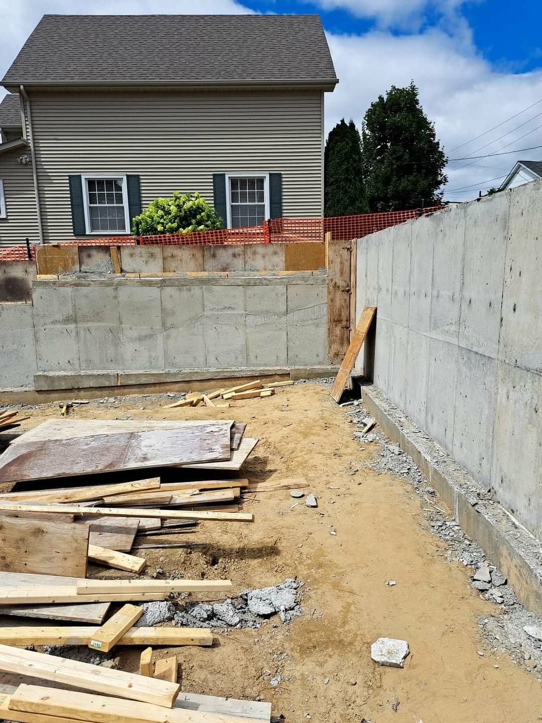 Completed concrete foundation walls stripped of forms beside a detached home